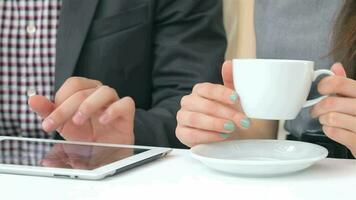 Close-up of hands show on the tablet, cups of coffee video