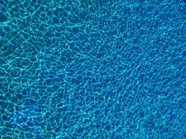 Blue water ripple in swimming pool with sun reflections photo