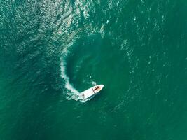 Aerial view of Speed boat in the aqua sea making a circle, Drone view photo