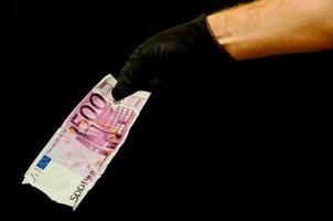 a person in black gloves holding a bank note photo