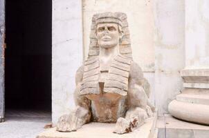 a statue of a sphinx is sitting on the ground photo