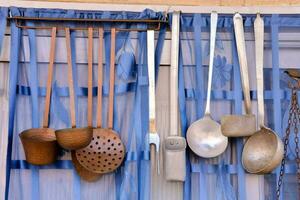 a collection of kitchen utensils hanging from a blue curtain photo