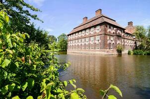 a large brick building sits next to a river photo