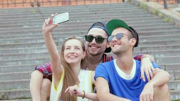 alegre menina sentado em a passos do dele amigos faz selfie video