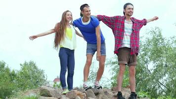 Three friends standing on the rocks at the river and flap their hands video