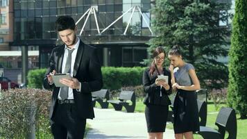 Confident businessman works on the tablet and then glances towards video