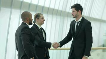 Four smiling successful businessmen shake hands with each other video