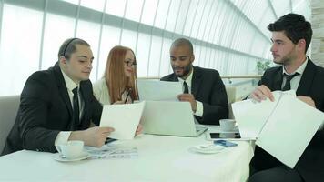vier glimlachen geslaagd zakenlieden zittend Bij tafel in kantoor video
