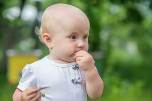 child eats green cherry berries in summer.portrait of todler against a backdrop of green trees. Danger of poisoning with unwashed fruit. photo