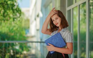 Girl schoolgirl covered her face with book. The child looks out from behind a large purple notebook. photo