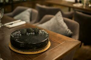 Black chocolate cake on a wooden table. Decorated with chocolate chip cookies birthday cake on a restaurant photo