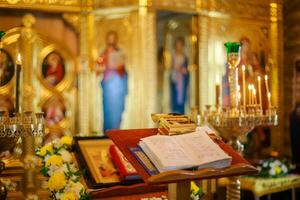 Open bible lying on the altar at the king's gate in the church. The box with things for anointing the child during the christening of the Orthodox church. Soft focus Defocused photo