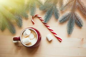 ed cups with hot chocolate or cocoa and marshmallow with candy cane. Christmas concept with fir tree branches. Close-up, selective focus photo
