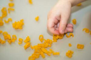 hand of child collecting letters from pasta from table. development of fine motor skills of hands. Montessori technique. Learn letters and alphabet in game photo