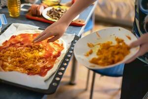 mano agregando ingredientes en hecho en casa Pizza. sencillo comida hecho desde barato alimentos preparando comida a hogar. foto