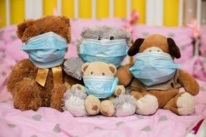 A group of toy animals in medical protective masks in a cot. Playing doctor. Sick animals during the epidemic. photo