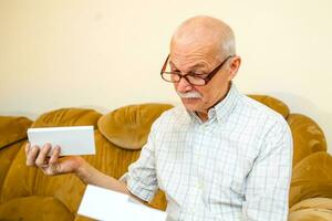 old man opened box with new phone. elderly man received birthday gift. pensioner holds parcel from an online store. photo