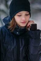 The girl looks down with a hand to her cheek. Warmly dressed child in winter on the street. photo