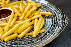 Plates of french fries on plates on a black stone table. Ready-to-serve meals for restaurant. Fast food photo