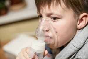 Asthma COPD Breath Nebulizer Mask on the Face of a Boy Being Treated. Child asthma inhaler, nebulizer steam, flu or cold concept. Copyspace photo