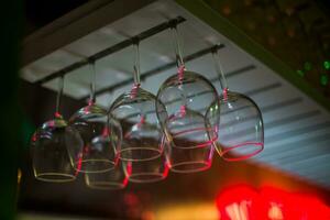 Bocals hanging on the bar. Wine glasses in a restaurant at a party. Light music and laser show in bar or cafe. photo