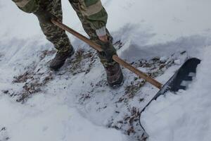 hombre borra el yarda de nieve con pala. pesado nevada en invierno. alto nivel de nieve. Nevado ventisquero. foto