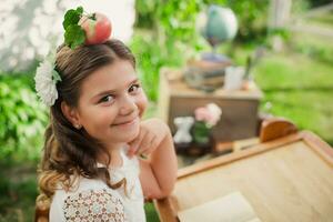 beautiful girl at desk with red apple on head. Learning outside the auditorium during coronavirus quarantine. Back to school concept. photo