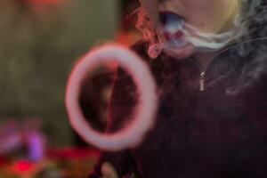 Circle of smoke from electronic cigarettes. Couples from vape. Smoke from the mouth of a smoking man. Men vaping and lets out circles of smoke. photo