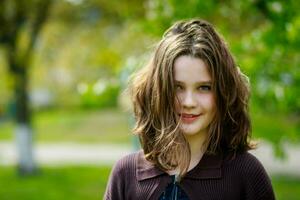 Beautiful girl among cherry flowers in spring. Portrait of a girl with brown hair and green eyes. photo