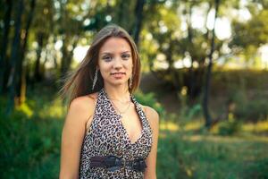 Beautiful girl in a light sarafan with developing hair on forest background. Girl is smiling standing. photo