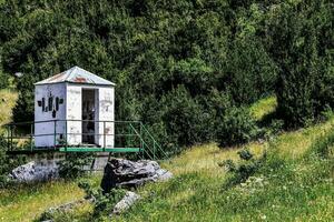 an old outhouse on a hillside near a forest photo