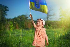 niña participación bandera de Ucrania. azul amarillo bandera de Ucrania con Saco de brazos en manos de niño en independencia día y bandera día. foto