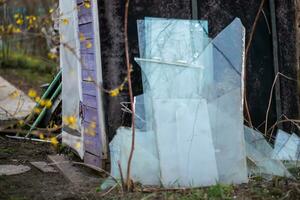 Shards of glass from windows standing near wall. Separate waste collection in yard. old destroyed house. photo