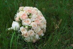 Bridal bouquet lying on the green grass photo