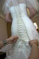 Friend of the bride bride corset laces on a wedding dress photo