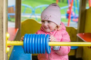 child in playground learns mathematics counting on large toy educational abacus. Wooden rings for learning account for children in elementary age. Little girl having fun outdoor photo