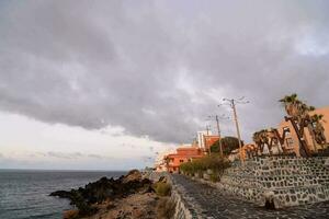 a rocky path leads to the ocean and buildings photo