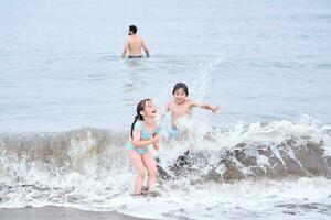 un chico y un niña son teniendo divertido jugando en el mar. foto