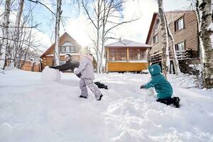 A family builds a snowman out of snow in the yard in winter. photo