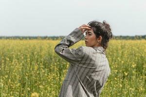 un asiático modelo poses en un campo de amarillo flores para un ropa marca, polietileno es el principal accesorios para un foto disparo.