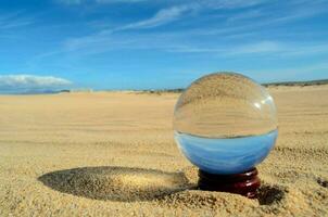 a glass ball sitting in the sand photo