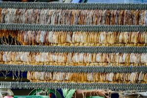 a man is working on a rack of dried fish photo