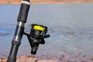 a fishing rod and reel on the shore of a lake photo