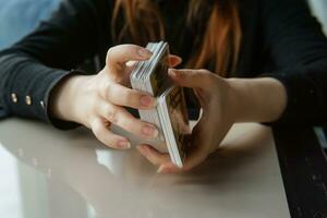 TVER, RUSSIA - FEBRUARY 11, 2023. Tarot cards, Tarot card divination, esoteric background. A woman makes a layout on the cards at the table. Divination, predictions on tarot cards. photo