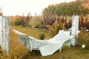 A hammock with pillows and a blanket on the street in the courtyard of a village house. A place to relax in the country. The concept of autumn photo