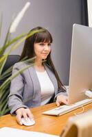 A brunette woman at a computer in the workplace. Business concept. photo