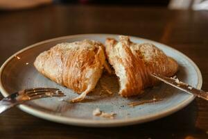 Cutting a croissant on a plate, close-up photo