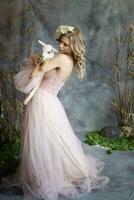 A young blonde woman in an airy pink dress with a white kid. Spring portrait of a woman. photo