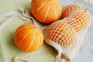 Mesh shopping bag with vegetables. Autumn pumpkin harvest photo