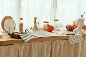 Kitchen countertop by the window in a bright room. Orange pumpkins, bread and pasta on the countertop. Autumn mood at home. photo